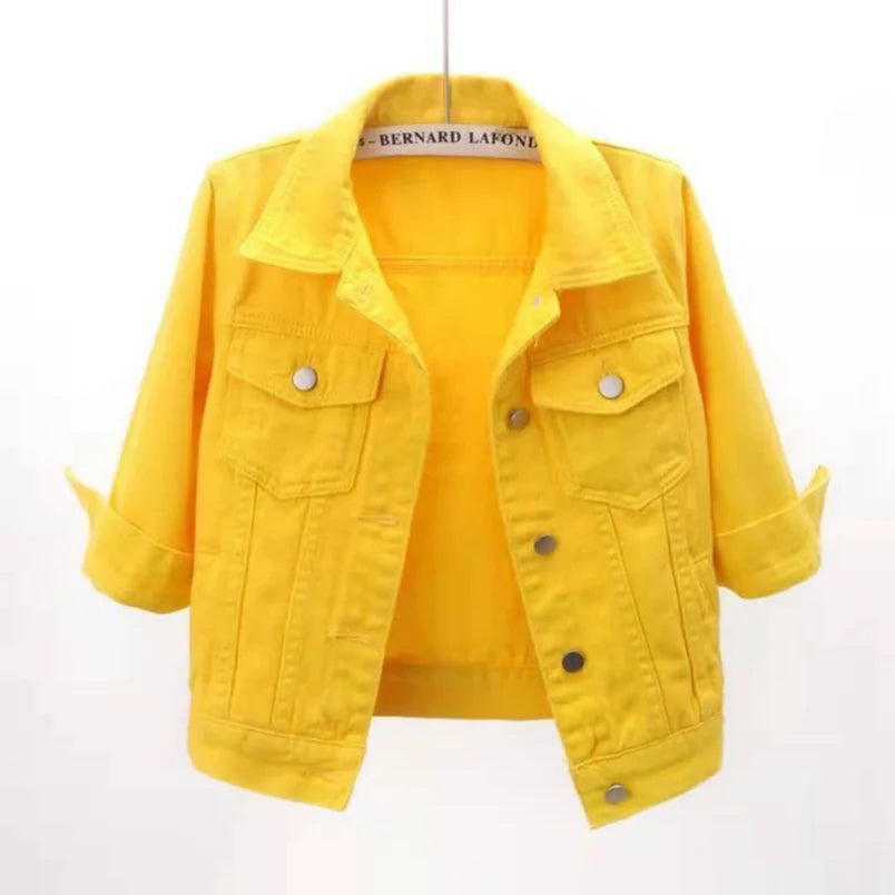 Cropped yellow denim jacket with spread collar, chest flap pockets and silver snap buttons, shown hanging open
