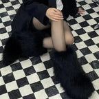 Model seated on a checkered floor wearing black fluffy fur boots, side and angled view