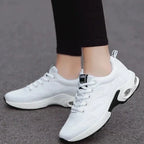 White lace-up women's sneakers with air cushion midsole windows, worn with black leggings, side view on pavement