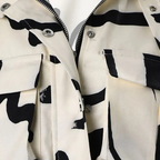 Close-up of the chest area showing the double flap cargo pockets, silver snap buttons and center-front zip on the printed jacket