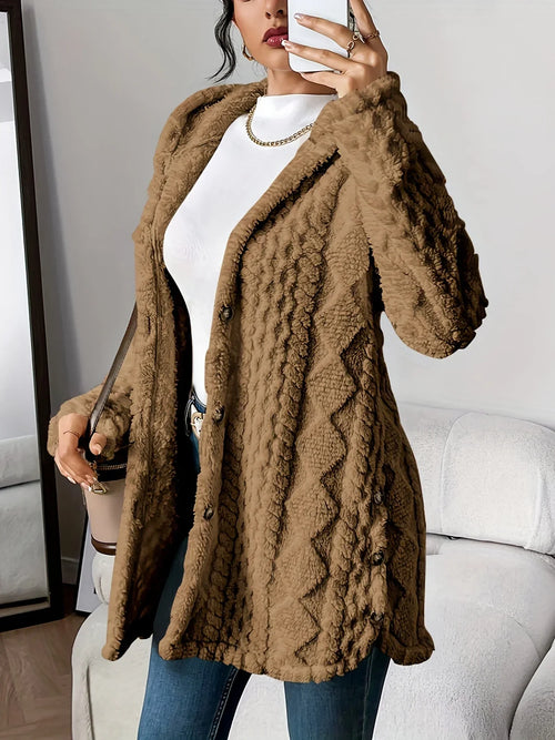 Mirror selfie view of a woman wearing an oversized hooded cardigan in camel brown with a raised diamond-texture surface, paired with a white turtleneck and jeans
